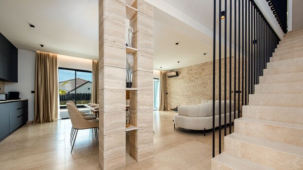Een modern interieur met een trap, een eetgedeelte en een zithoek.