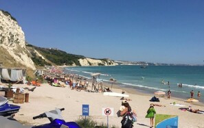 Una playa con un letrero que dice 'FREE ZONE', sombrillas y gente tomando el sol.