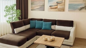 Uma sala de estar moderna com um sofá seccional, uma mesa de centro e três quadros na parede.