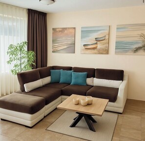 Una sala de estar moderna con un sofá modular, una mesa de centro y tres cuadros en la pared.