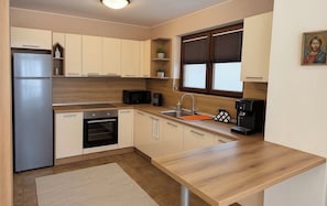 Eine moderne Küche mit Kühlschrank, Mikrowelle, Backofen, Spüle und Kaffeemaschine.