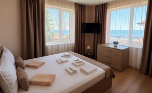 Habitación de hotel con cama, escritorio, televisor y vista al mar.