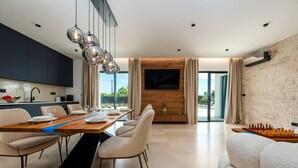 A modern dining area with a long table, chairs, and a chessboard. - Villa Krišto ZadarVillas (Privlaka)
