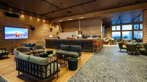 A modern interior with wooden walls, a bar area, seating, and a large TV screen. - Kaamos Lodge (Ylitornio)