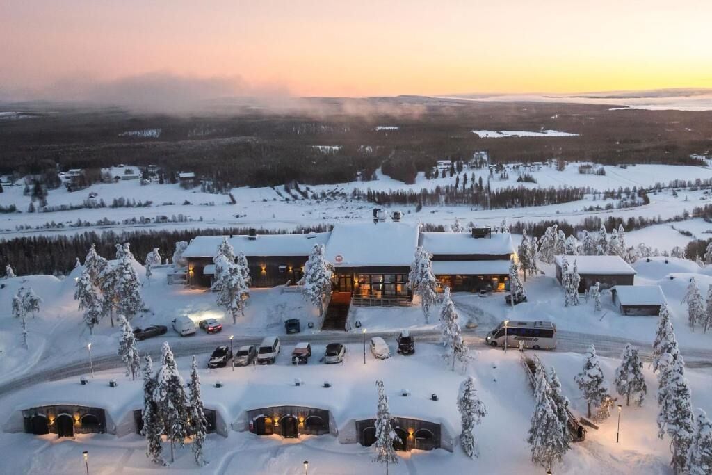 A snow-covered building with multiple parking spaces and a few cars.
