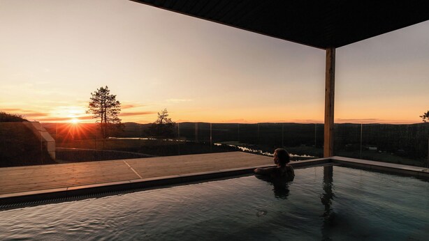 En modern infinitypool med fri sikt över solnedgången och det avlägsna landskapet.