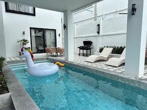 A swimming pool with a swan float, outdoor furniture, and a grill. - Lune&Palm Pool Villa (Pattaya City)