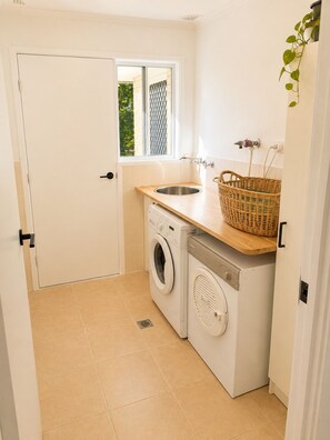 Ein kleiner Hauswirtschaftsraum mit Waschmaschine, Spüle und Fenster.