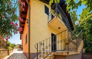 Ein zweistöckiges Gebäude mit einer Steintreppe, einem Balkon und einer Tür zum Eingang.