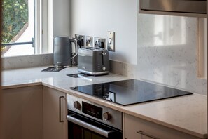 A modern kitchen with a built-in stovetop, a kettle, and a toaster. - Marine Place | Flat 10 (St Andrews)