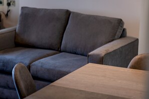 Ein graues Sofa mit einem Couchtisch aus Holz in einem Zimmer.