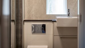 A bathroom with a built-in washing machine, a mirror, and a sink. - Marine Place | Flat 8 (St Andrews)
