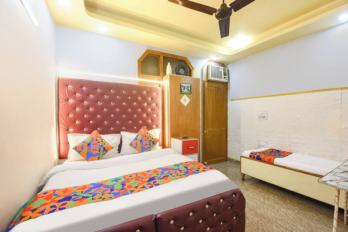Una habitación de hotel con una cama grande, una cama más pequeña, un armario y un ventilador de techo.