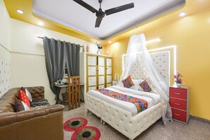 Quarto com cama, sofá, guarda-roupa, ventoinha no teto e mesa de cabeceira.