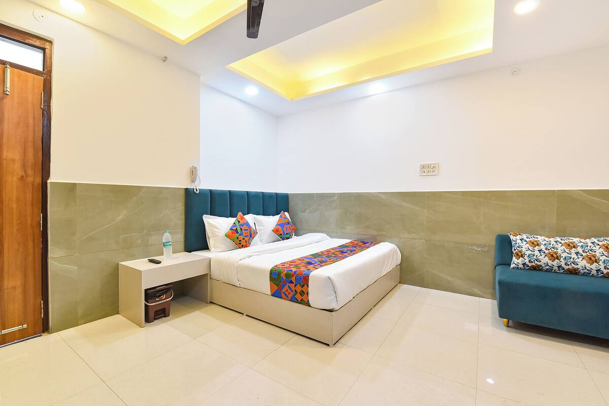 A hotel room with a bed, bedside table, and a sofa.