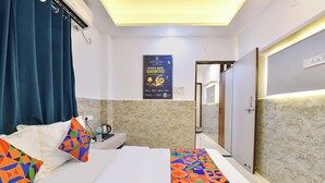 A hotel room with a bed, a nightstand, a poster, a door, and a wall with a textured pattern. - FabHotel Metro Residency (Indore)