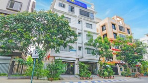 Un hotel de varios pisos con un llamativo letrero de 'Tab Hotels', múltiples balcones y una variedad de plantas en macetas al frente.