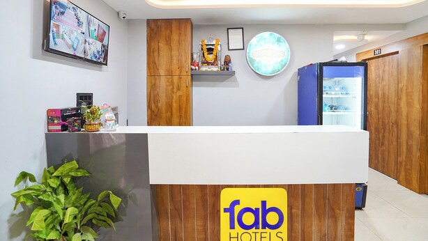 A reception desk with a 'fab hotels' sign, a security camera, a wall-mounted TV, and a refrigerator. - Fabhotel Royal King (Ahmedabad)
