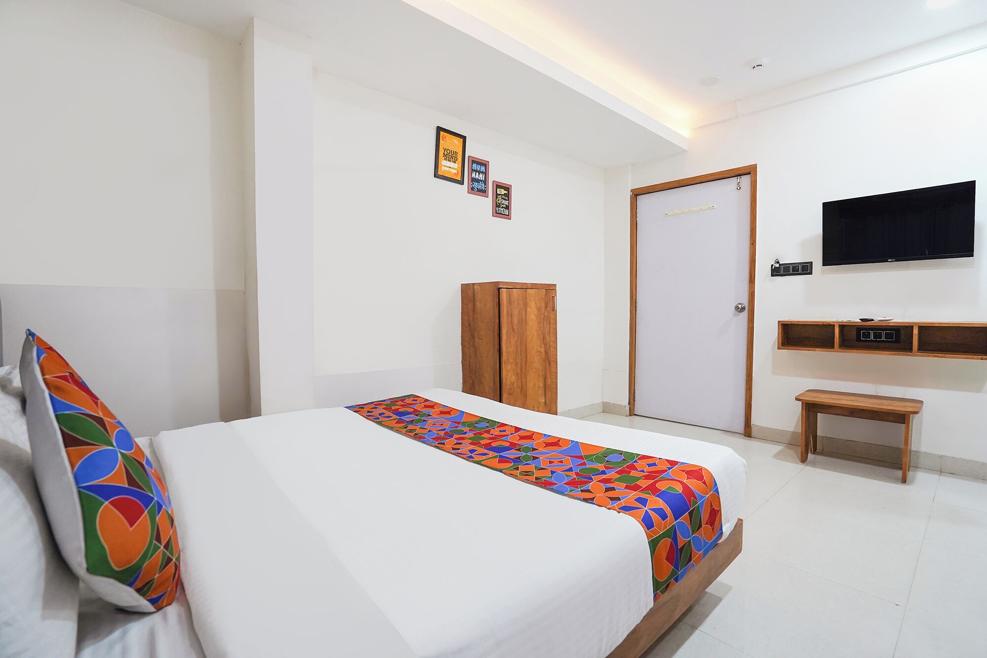 Una camera da letto con un letto, un armadio in legno, una televisione e un piccolo tavolino.