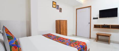 Una camera da letto con un letto, un armadio in legno, una televisione e un piccolo tavolino.