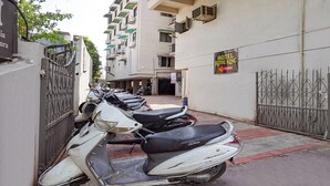 A row of parked scooters, a gated entrance, and a sign for the Royal King Hotel on the 3rd floor. - Fabhotel Royal King (Ahmedabad)
