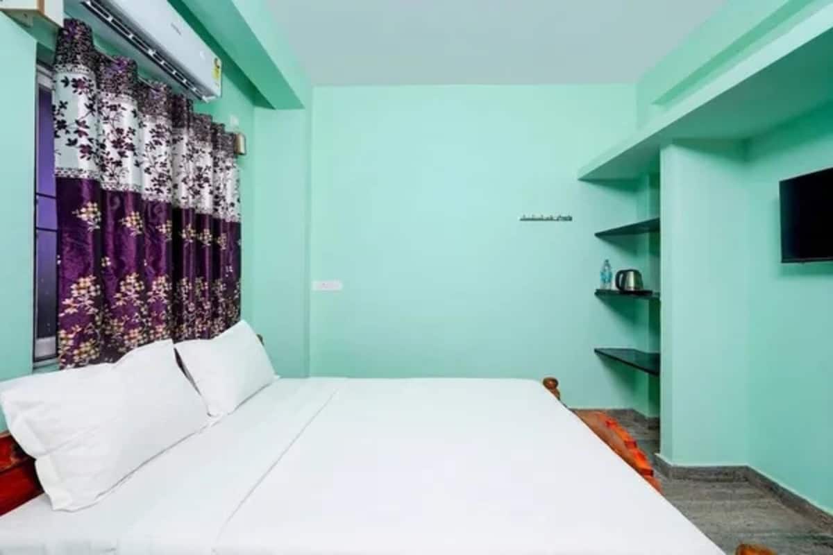 Ein Zimmer mit einem Bett, einem Fernseher an der Wand und einem Regal mit Gegenständen.