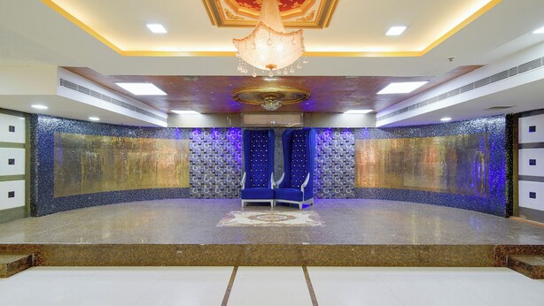 A spacious room with a central stage, a chandelier, and a patterned wall. - Fabhotel Regal I (Hyderabad)