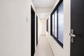 A corridor with doors, a light switch, and a window with blinds. - Via Nisarg Blue (Alibag)