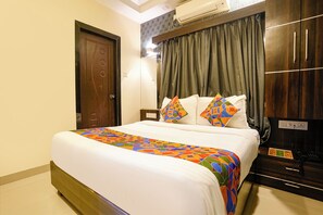 Une chambre d’hôtel équipée d’un lit, d’une armoire, d’un bureau avec un téléphone et d’un climatiseur fixé au mur.