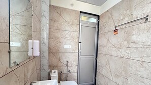 Et badeværelse med vask, toilet og bruser.