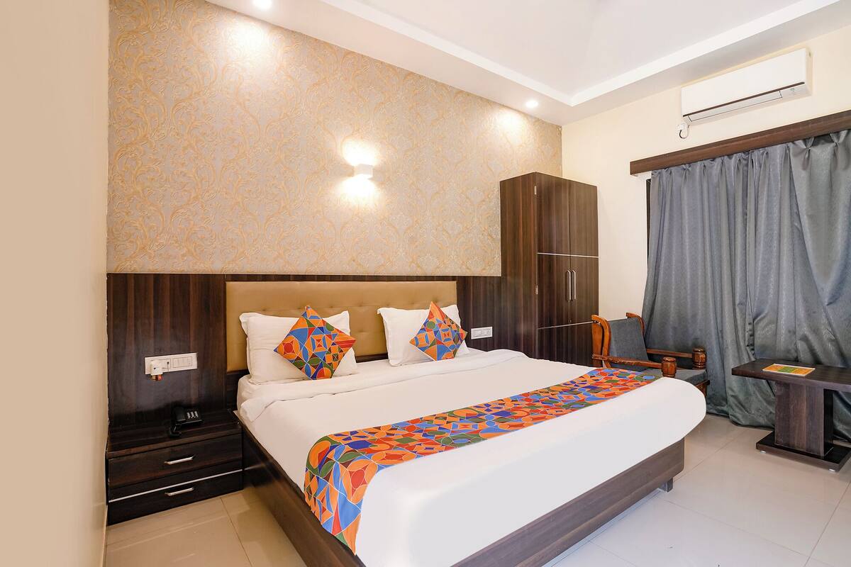 A hotel room with a large bed, a wardrobe, a desk, and a window with curtains.