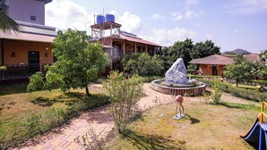 A courtyard with a water fountain, a playground, and a building with satellite dishes. - Fabhotel Prime Harmony Resort (Alibag)