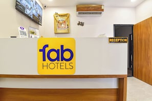 A reception desk with a 'fab hotels' sign, a 'reception' sign, a mounted television, and an air conditioning unit. - FabHotel AVR, Mahalaxmi Nagar (Indore)