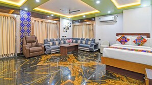 Ein Hotelzimmer mit einer Couch, einem Sessel, einem Bett, einem Couchtisch und einem Deckenventilator.