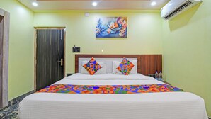 Quarto de hotel com uma cama, um quadro na parede, ar condicionado e uma porta.