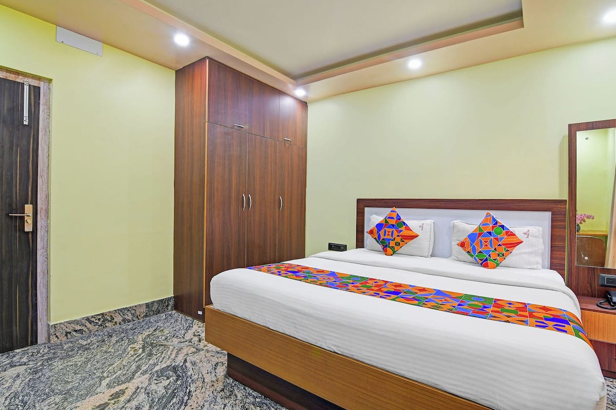 A hotel room with a bed, a wardrobe, a nightstand, and a mirror.