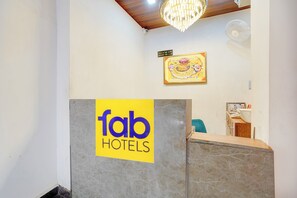 Una recepción con un letrero de 'fab hotels', una obra de arte enmarcada y un candelabro.