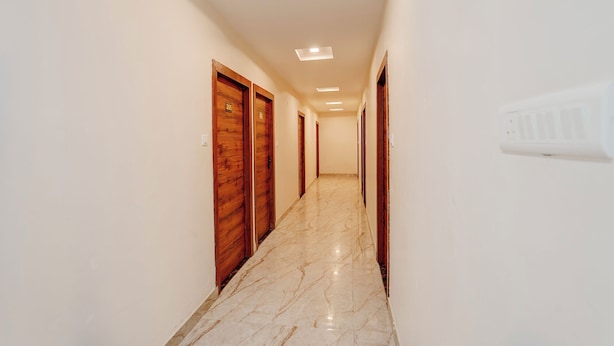 A hallway with wooden doors, a marble floor, and recessed ceiling lights. - FabHotel Southtown - Near Govindpuri Railway Junction (Kanpur)