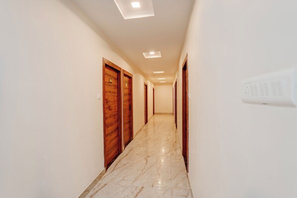 A hallway with wooden doors, a marble floor, and recessed ceiling lights. - Fabhotel South Town - Near Govindpuri Railway Junction (Kanpur)