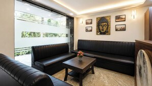 A modern interior with a black leather sofa, a wooden coffee table, and a Buddha artwork on the wall. - FabHotel Karol Bagh Residency - Nr. Karol Bagh Market (New Delhi)