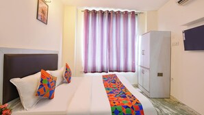 A hotel room with a bed, a wardrobe, a wall-mounted TV, and a window with curtains. - FabHotel Karol Bagh Residency - Nr. Karol Bagh Market (New Delhi)