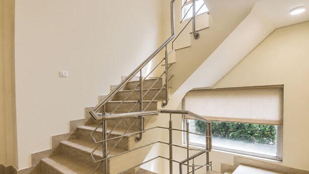A modern staircase with metal railings, a view of greenery outside, and a window with a view of the outdoors. - FabHotel Karol Bagh Residency - Nr. Karol Bagh Market (New Delhi)