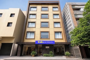 A multi-story hotel with a flat facade, large windows, and a sign for 'fabHOTELS' at the entrance.