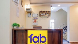 A reception desk with a 'fab hotels' sign, a calendar, and a framed picture on the wall. - Via Utsav Grand Inn - RR Nagar (Bangalore)