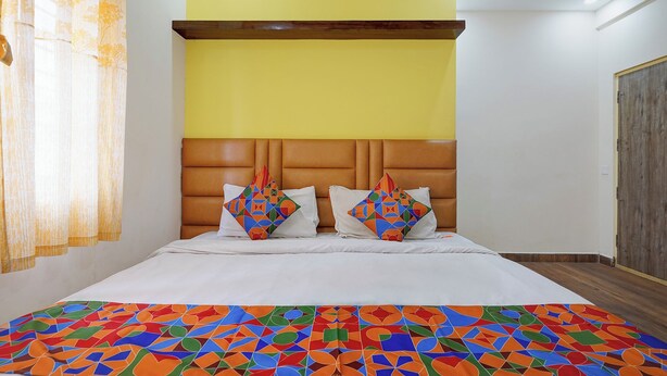 A bed with a patterned bedspread, a headboard, and two pillows with geometric designs. - Via Utsav Grand Inn - RR Nagar (Bangalore)