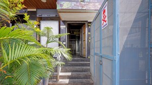 A narrow outdoor corridor with steps leading to a building entrance, surrounded by greenery. - Via Utsav Grand Inn - RR Nagar (Bangalore)