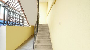 Eine Treppe mit Metallgeländer, einer gelben Wand und einer blauen Matte am unteren Ende.