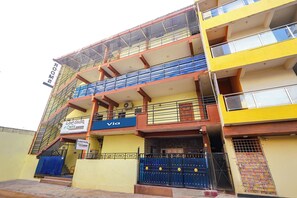A multi-story building with balconies, a blue sign for 'ONYX,' and a yellow facade. - Via Onyx Residency (Bengaluru)