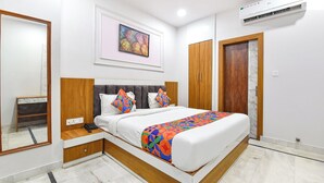 Quarto com cama, mesas de cabeceira, guarda-roupa, espelho e ar condicionado.