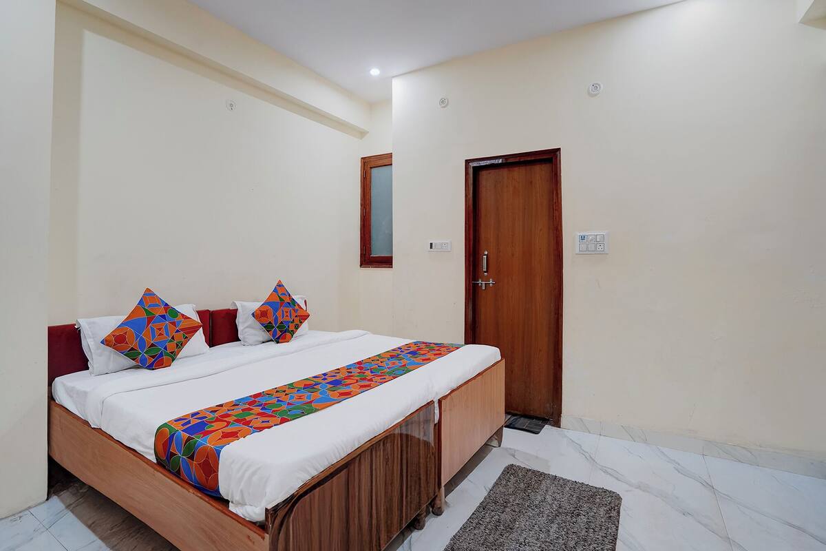 A bedroom with a wooden bed, white bedding, and a colorful geometric-patterned throw.